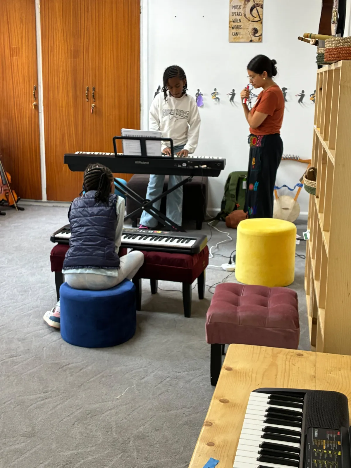 Campers playing keyboards while their music teacher guides the session in the music room