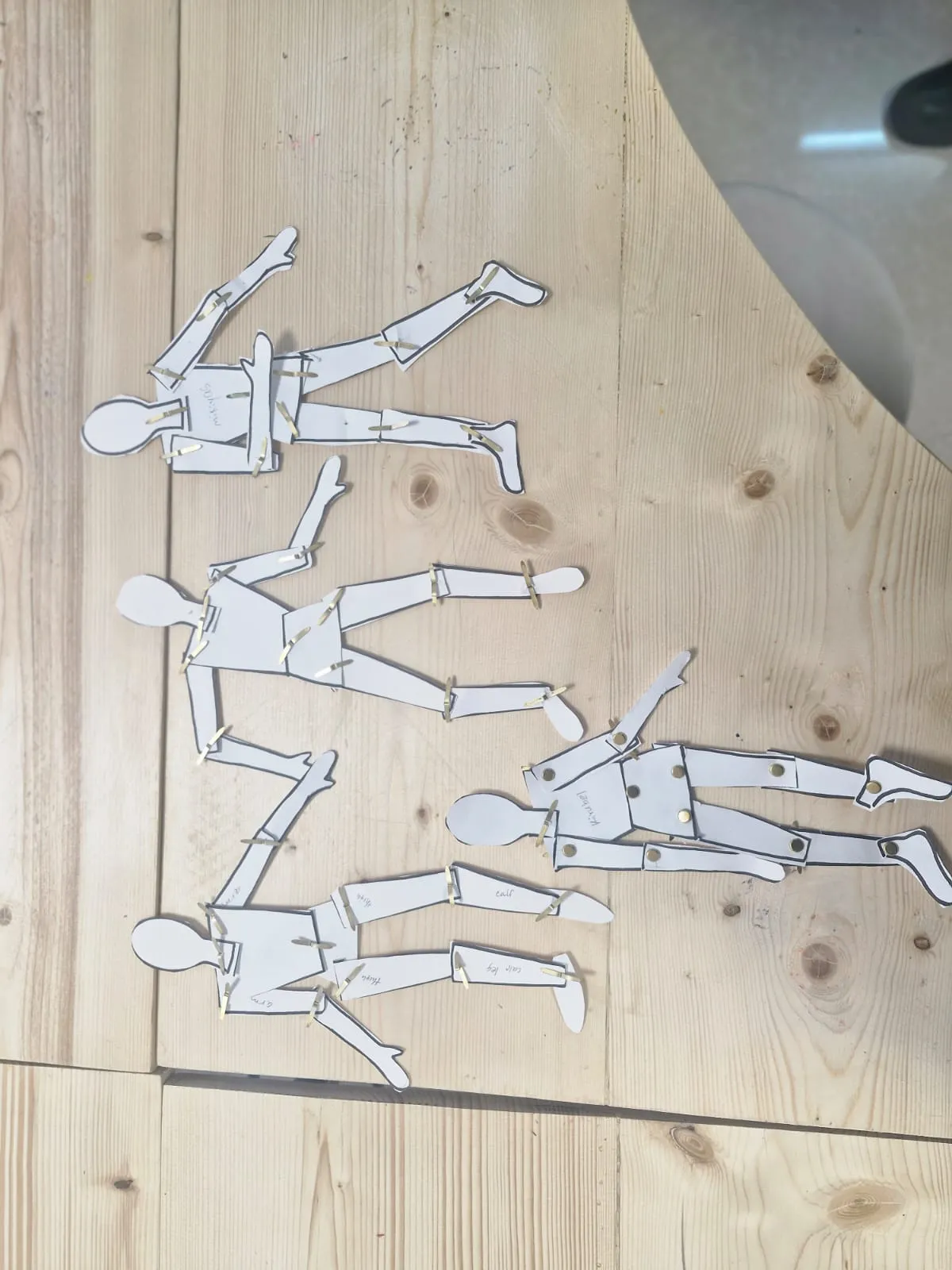 Articulated paper Shape Men with fastener joints laid out on a wooden art table