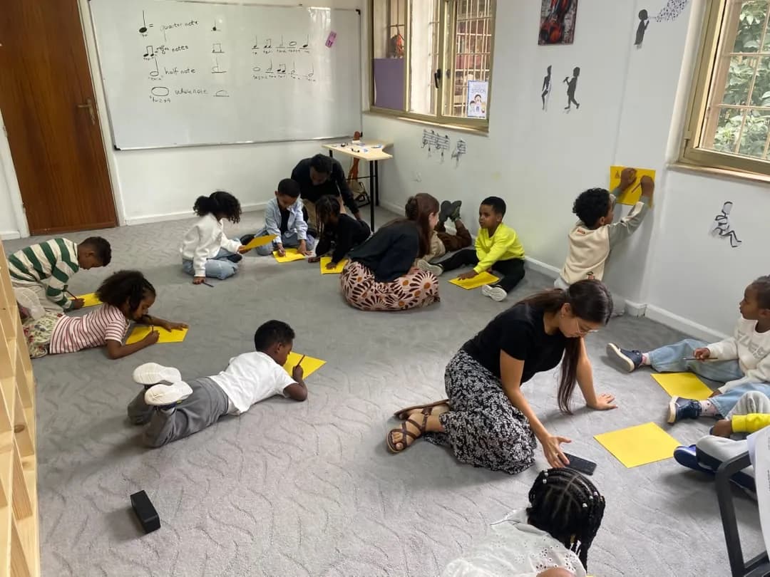 Campers working on yellow paper craft projects on the classroom floor with their teachers