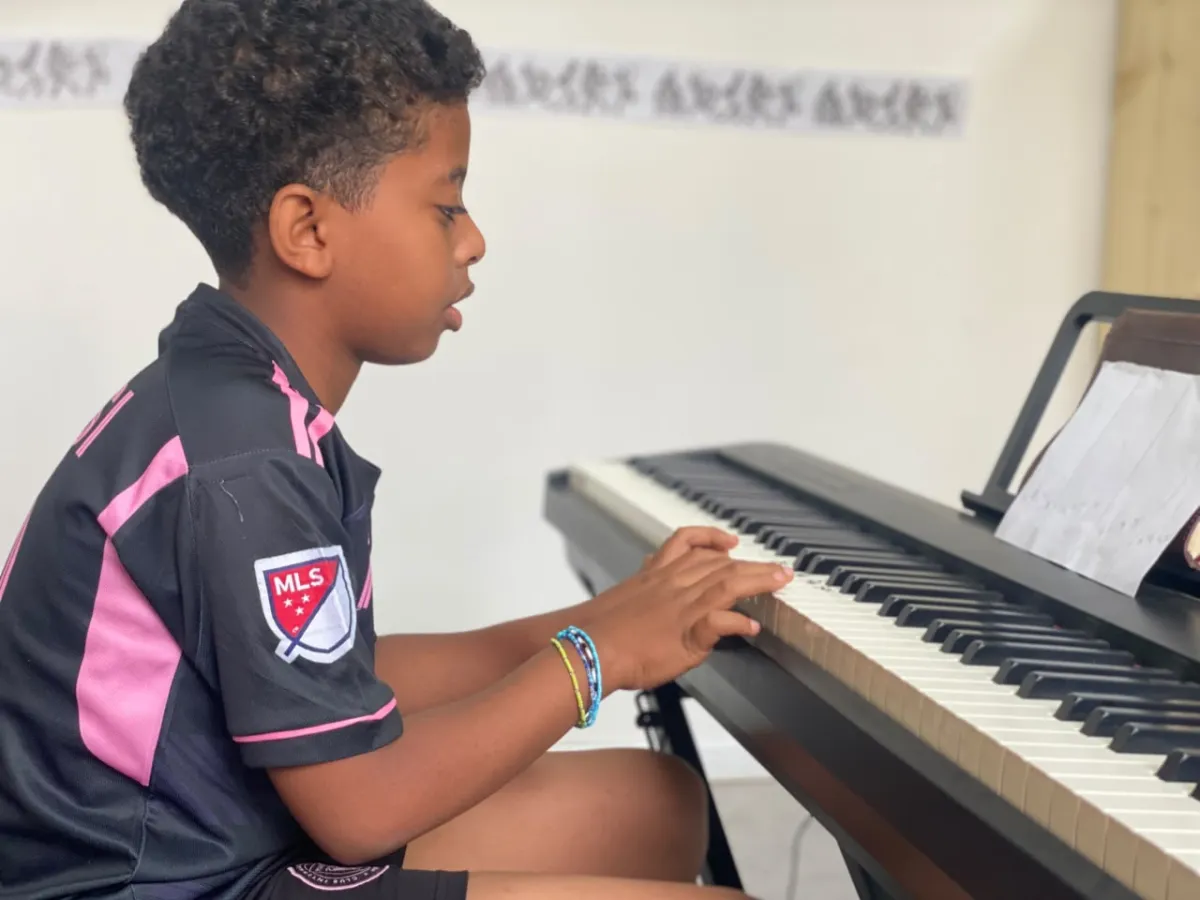 A camper working through a keyboard exercise with his sheet music propped on the stand