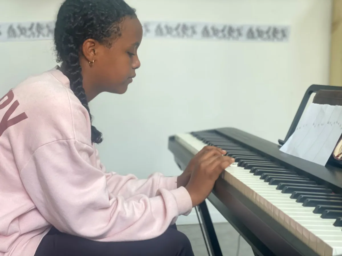 A camper practising her keyboard piece from handwritten notes in the music room