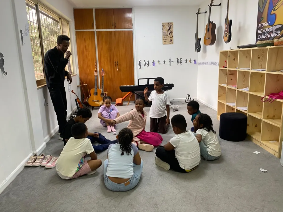 The music teacher leading a circle of campers seated on the floor of the music room