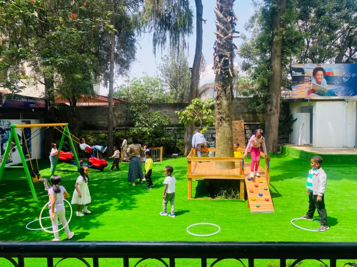 The playground busy with campers on the swings, the climbing frame and hula hoops under the big palm tree