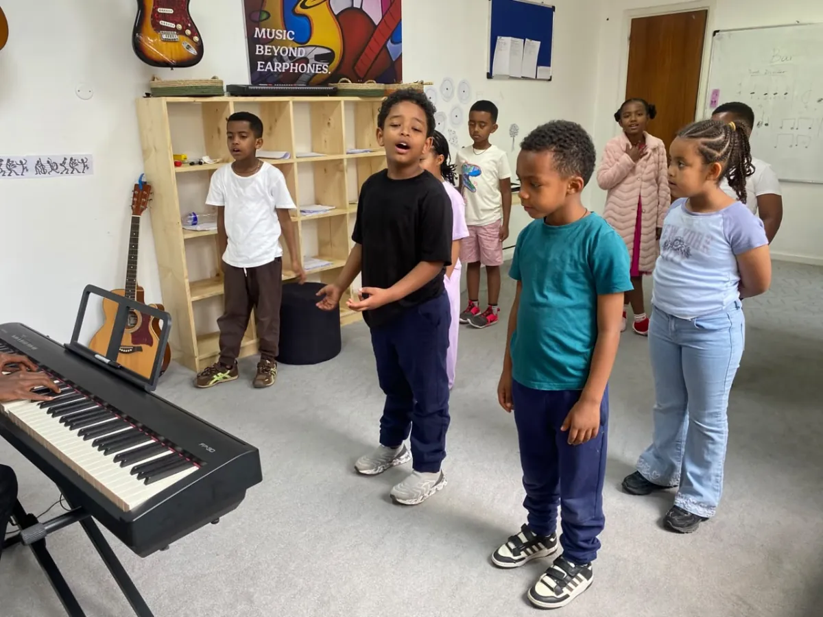 A camper singing out mid phrase while the rest of the group sings along beside the piano