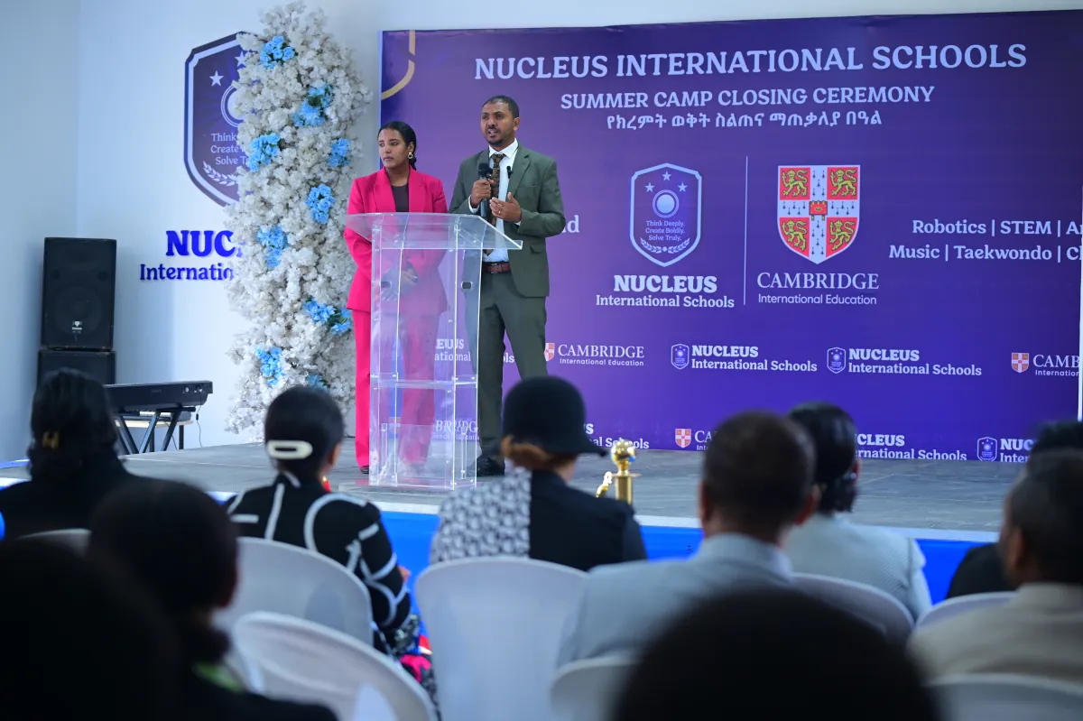 The stage at the Nucleus International Schools summer camp closing ceremony in Addis Ababa, with a host at the podium and parents seated in front