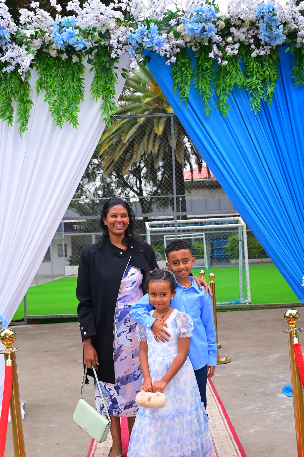 A parent photographed with her children and their summer camp certificates at the Nucleus campus