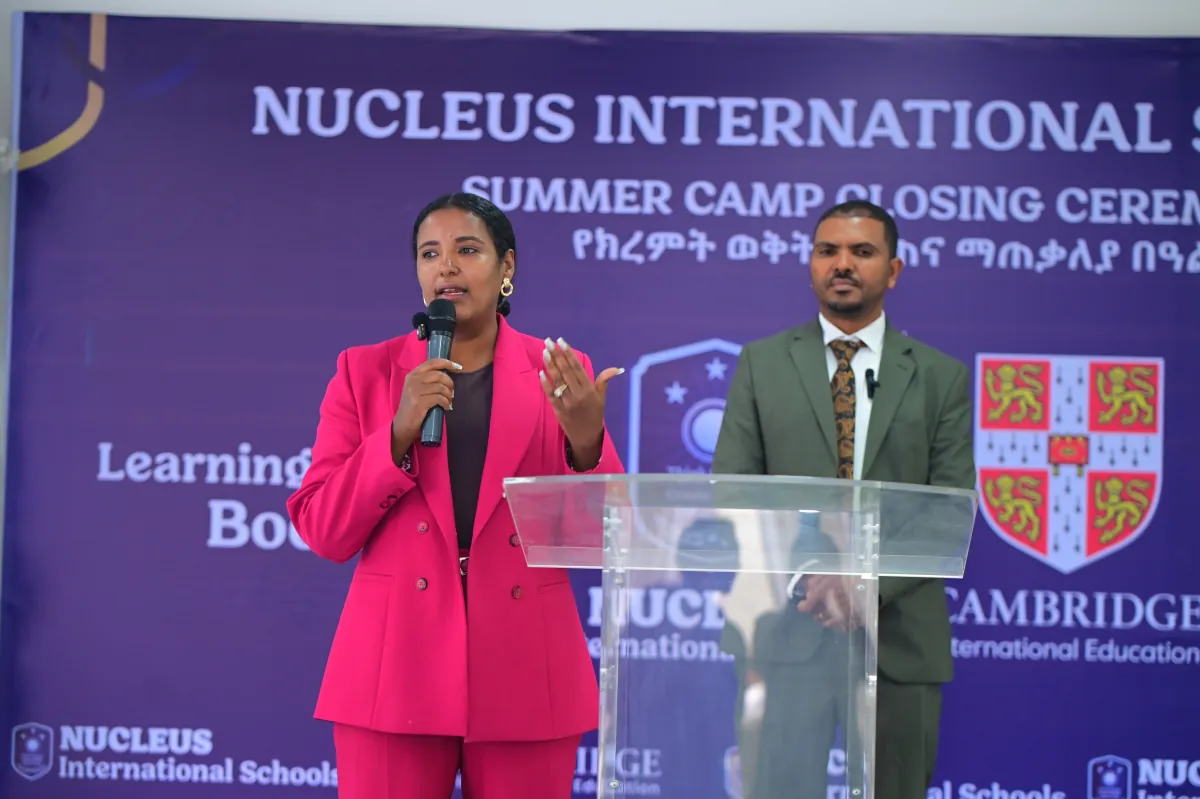 Two hosts opening the Nucleus International Schools summer camp closing ceremony from the podium