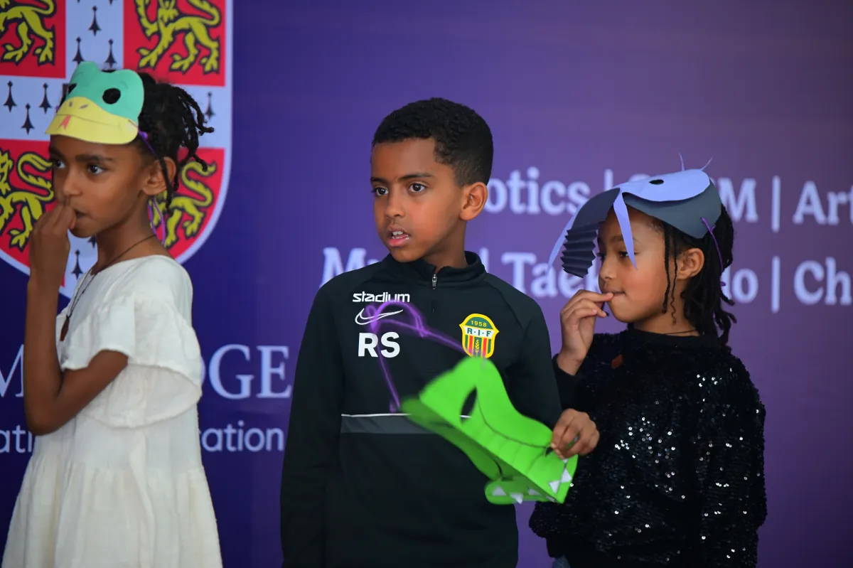 Campers on stage holding hand-made animal masks and a microphone during a drama performance