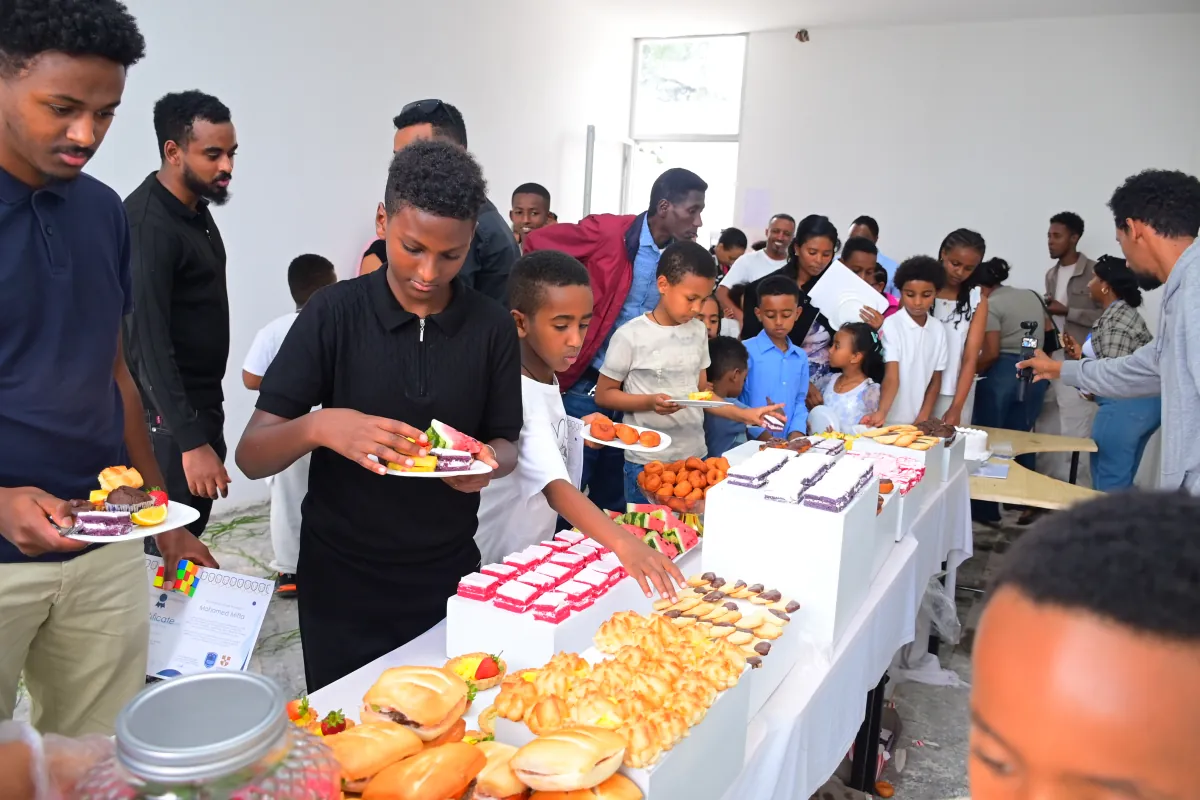 Campers queueing along the refreshments table for cake and pastries after the closing ceremony