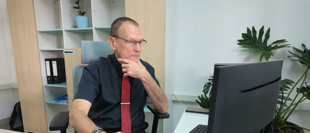 Daniel Hiest at his desk, hand on chin, reading through work on his computer