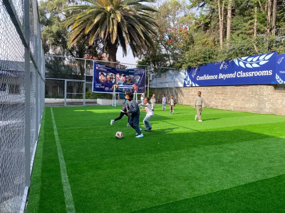 Two campers chasing the ball down the turf pitch during a five-a-side football game
